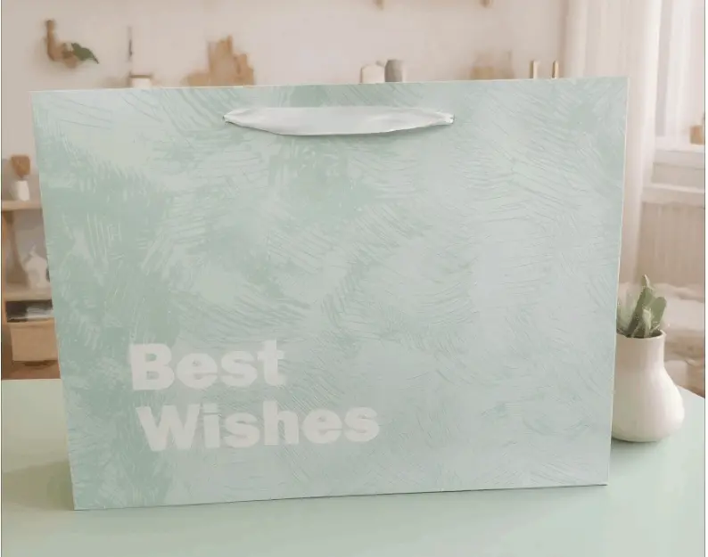 This handbag is named FH-22019-L Cross-border Wholesale Simple Cardstock Gift Bag with Good Wishes. It is made of high-quality cardstock material, which is crisp and well-shaped, and can firmly hold items. The surface is printed with fine techniques, with a light blue tone that is fresh and elegant. Paired with simple text patterns, it is simple yet stylish. The white handle design is in harmony with the color of the bag body and is also sturdy and durable. It is suitable for carrying goods and gift packaging when shopping, or for daily storage and carrying small items, etc. Whether it is for shopping or gift-giving occasions, it can show elegant taste.Product uses: Packaging paper bags, shopping paper bags, gift paper bags, festival paper bags, promotional paper bags.